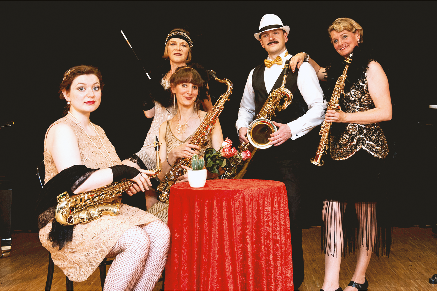 Ein Gruppenbild mit fünf Menschen, im Stil von zwanziger Jahre bekleidet mit Saxophonen in der Hand